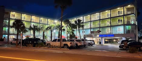 A multi-story hotel with balconies, a parking area, and a sign for 'Relican Pointe'.