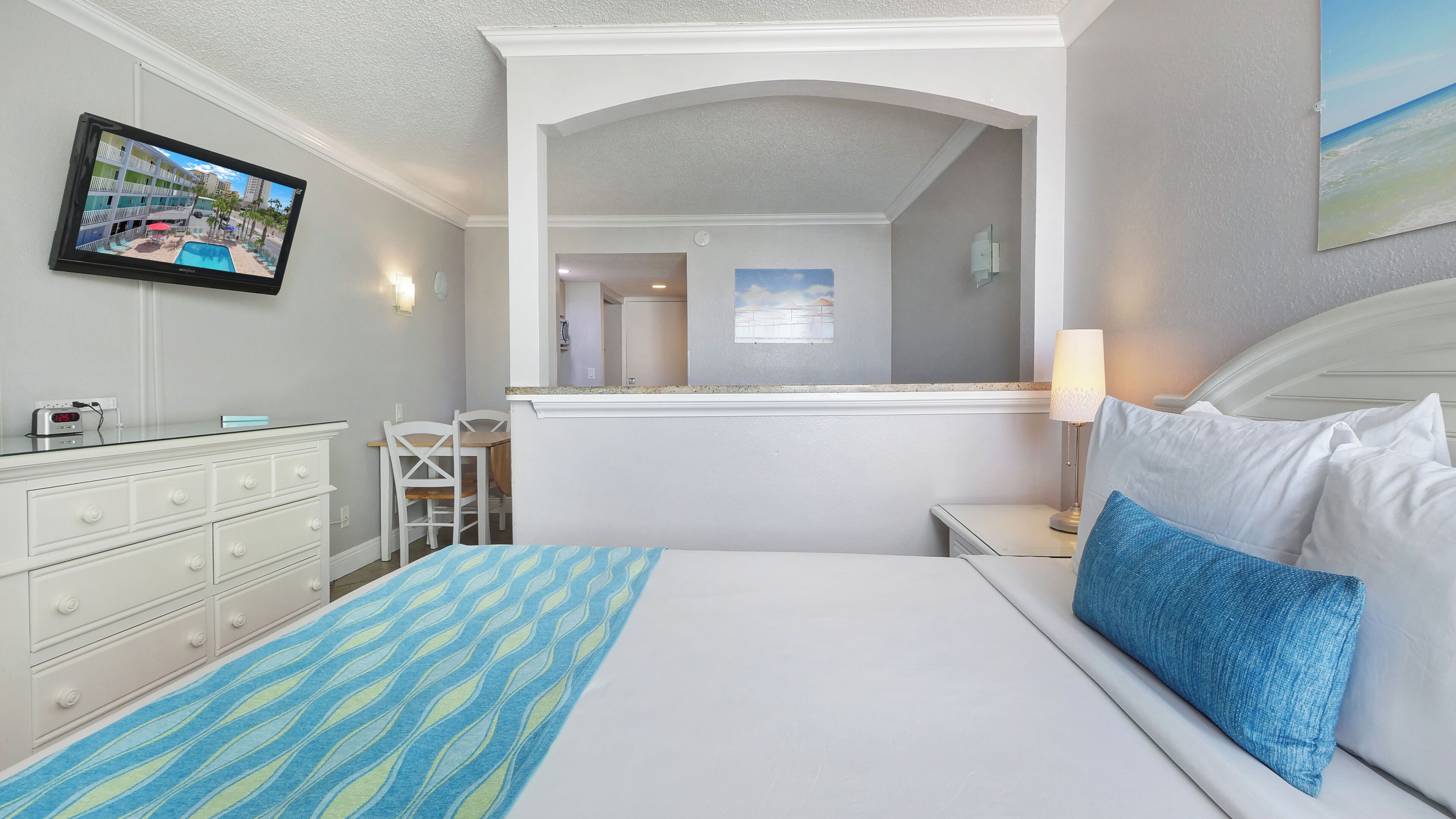 Una camera d'albergo con un letto, una scrivania, una sedia, una televisione e un quadro.