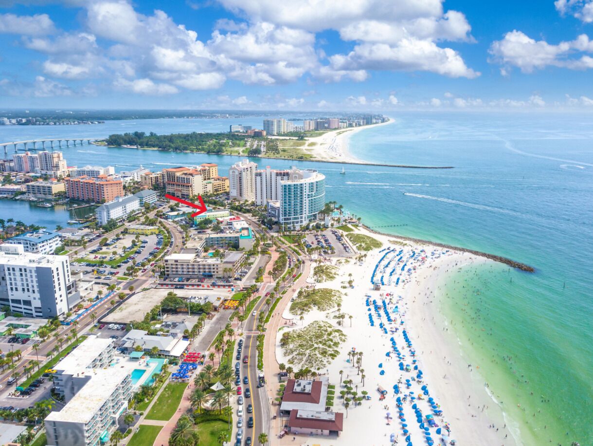 A coastal cityscape with a beachfront, hotels, and a bridge in the background.