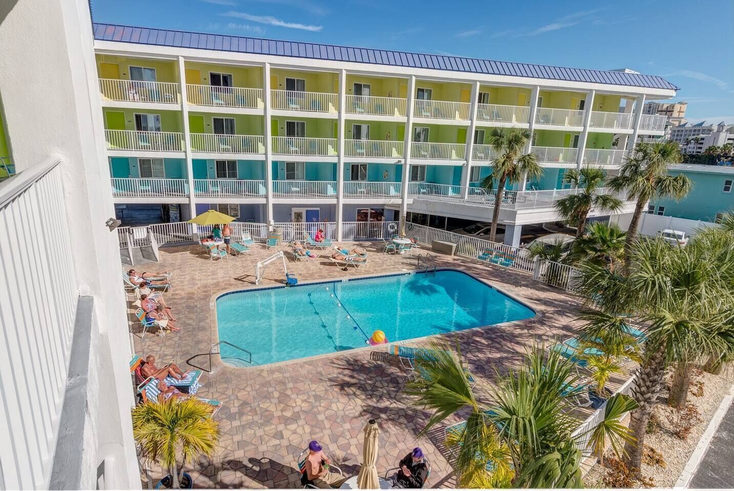 Um hotel com piscina, rodeado por espreguiçadeiras e palmeiras.
