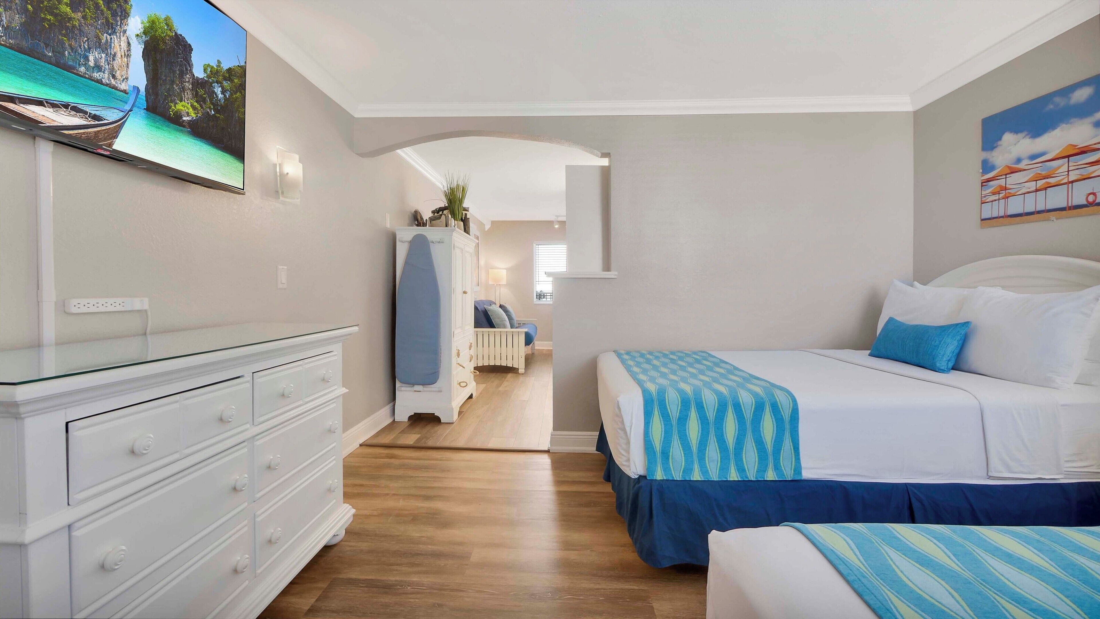 Ein Schlafzimmer mit einem Bett, einem Schminktisch, einem Fernseher und einem Gemälde.