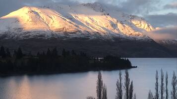 A mountain with snow-covered peaks and a calm lake in the foreground.
