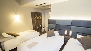 A hotel room with two beds, a seating area, a wooden door, and a wall-mounted light fixture. - Hearton Hotel Shinsaibashi (Osaka)