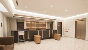 A modern reception area with a counter, seating, and an elevator. - Hearton Hotel Shinsaibashi (Osaka)
