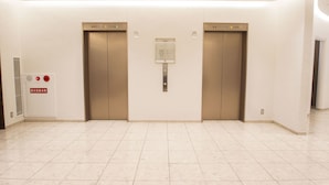 A modern elevator area with two elevators, a fire alarm panel, and a clear floor. - Hearton Hotel Shinsaibashi (Osaka)