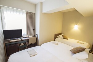 A hotel room with a bed, a desk with a television, and a nightstand.