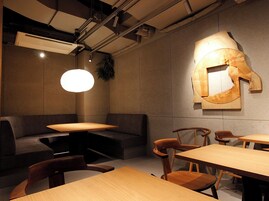 A modern dining area with a sofa, wooden tables, and chairs.
