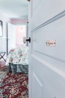 A white door with a nameplate reading "Aryana" and a floral-patterned bed in the background.