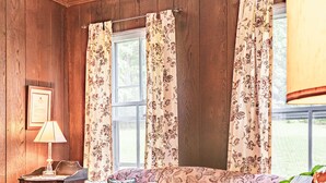A cozy room with a patterned sofa, a wicker coffee table, and a wooden desk with a lamp. - Black Mountain Inn (Black Mountain)