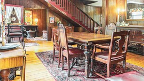 A dining room with a wooden table and chairs, a staircase, and a mirror. - Black Mountain Inn (Black Mountain)