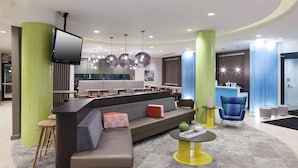 A modern lobby with a large sofa, a reception desk, and a bar area.
