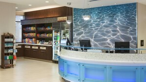 A modern bar area with a curved counter, a refrigerated display case, and a wall with a textured pattern.