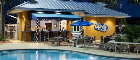 A poolside bar with outdoor seating and a sign that reads "Splash Bar & Grill".