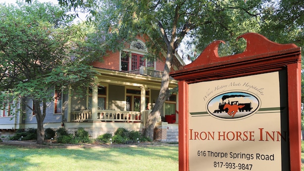 Une enseigne pour l’auberge Iron Horse, avec un cadre rouge classique et un logo représentant un cheval et un attelage. L’enseigne indique le nom de l’auberge, son adresse et son numéro de téléphone.