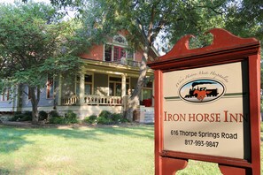A sign for Iron Horse Inn with a classic red frame and a logo depicting a horse and carriage. The sign includes the inn's name, address, and phone number. - Iron Horse Inn (Granbury)