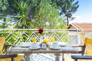 A table set for breakfast with plates, cups, and a pitcher of juice, surrounded by chairs and a decorative rose.