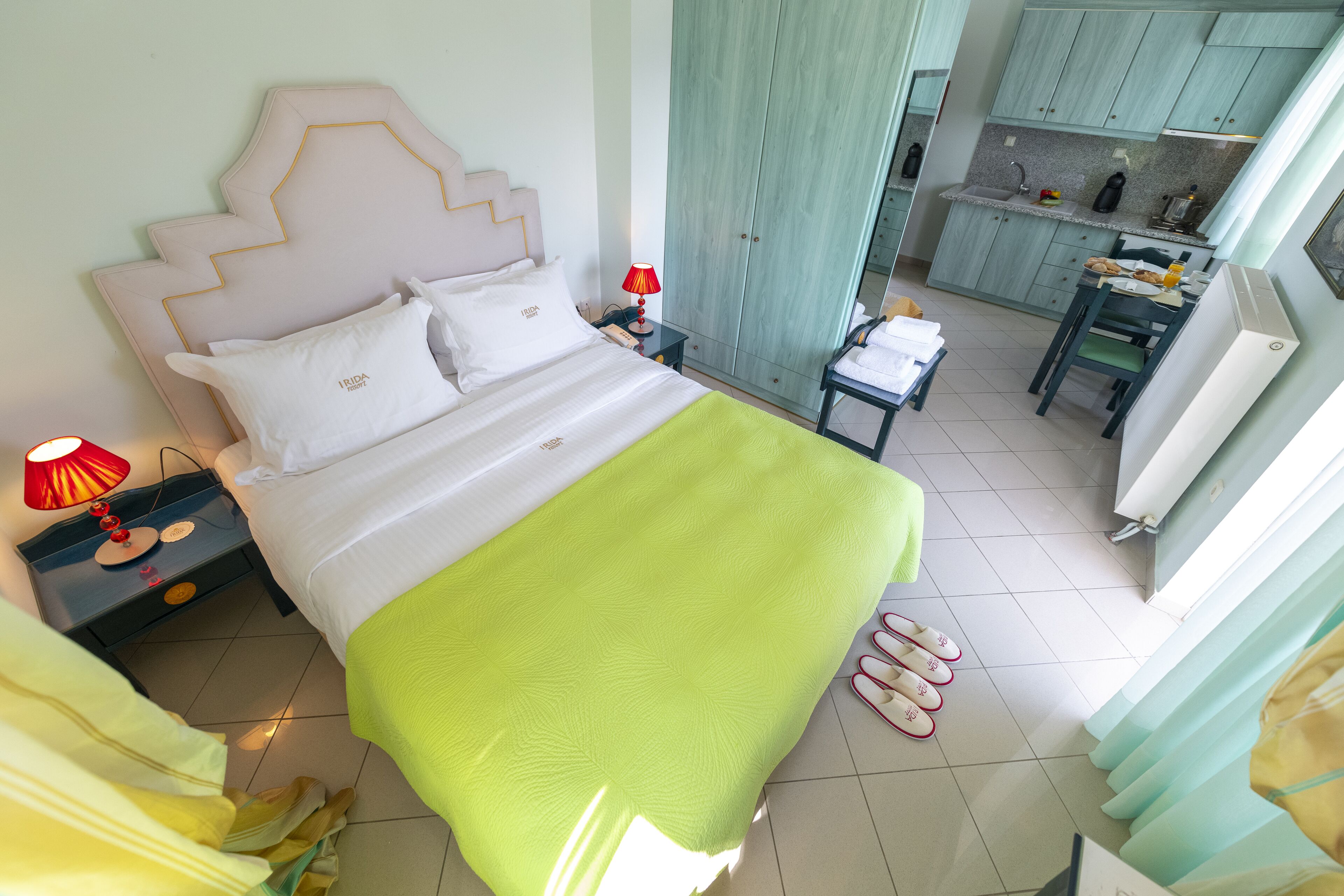 A neatly arranged bedroom with a bed, bedside table, lamp, and slippers.