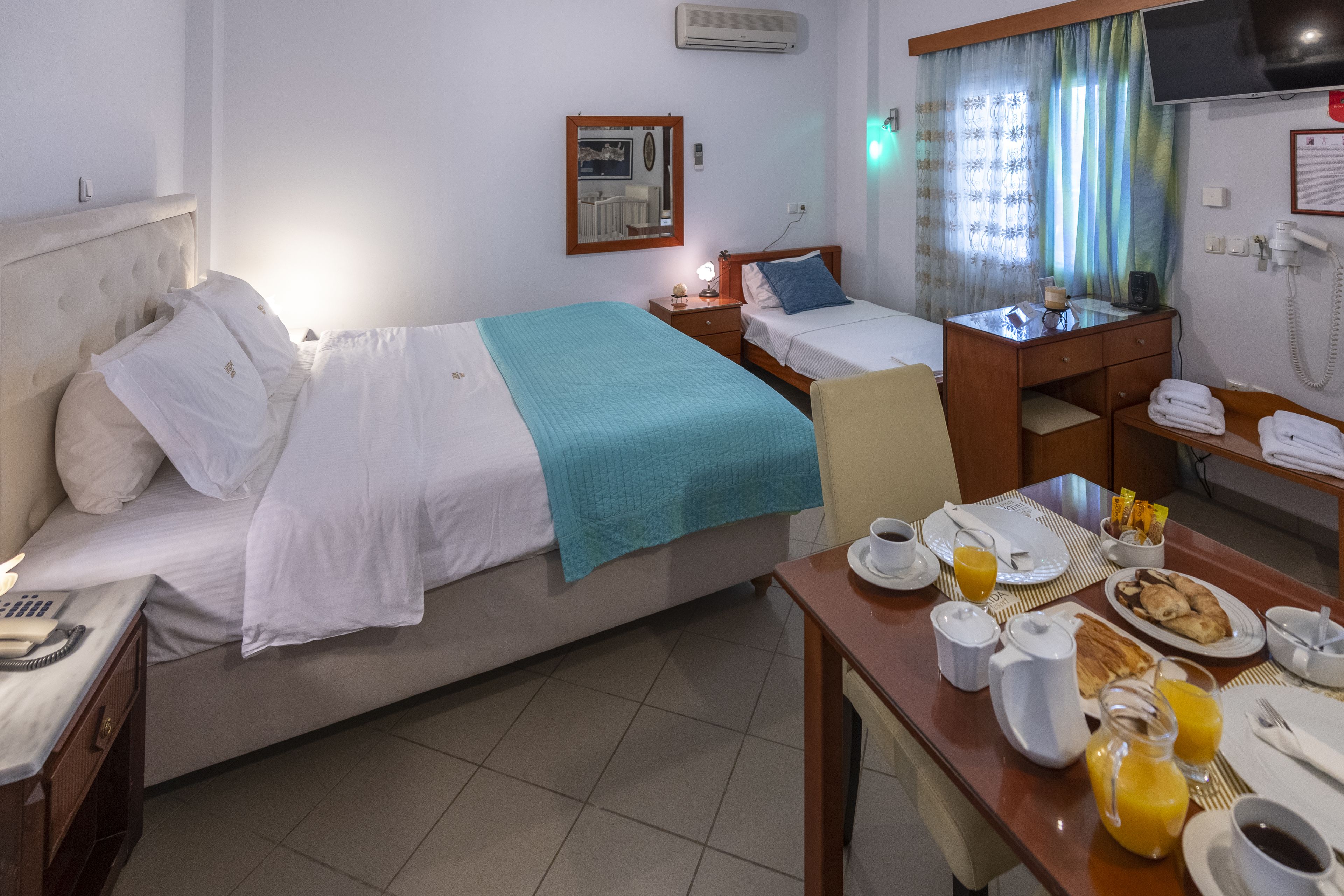 Une chambre d’hôtel équipée d’un lit, d’une table de chevet, d’un bureau et d’un coin pour prendre le petit-déjeuner.