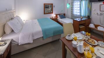 Une chambre d’hôtel équipée d’un lit, d’une table de chevet, d’un bureau et d’un coin pour prendre le petit-déjeuner.