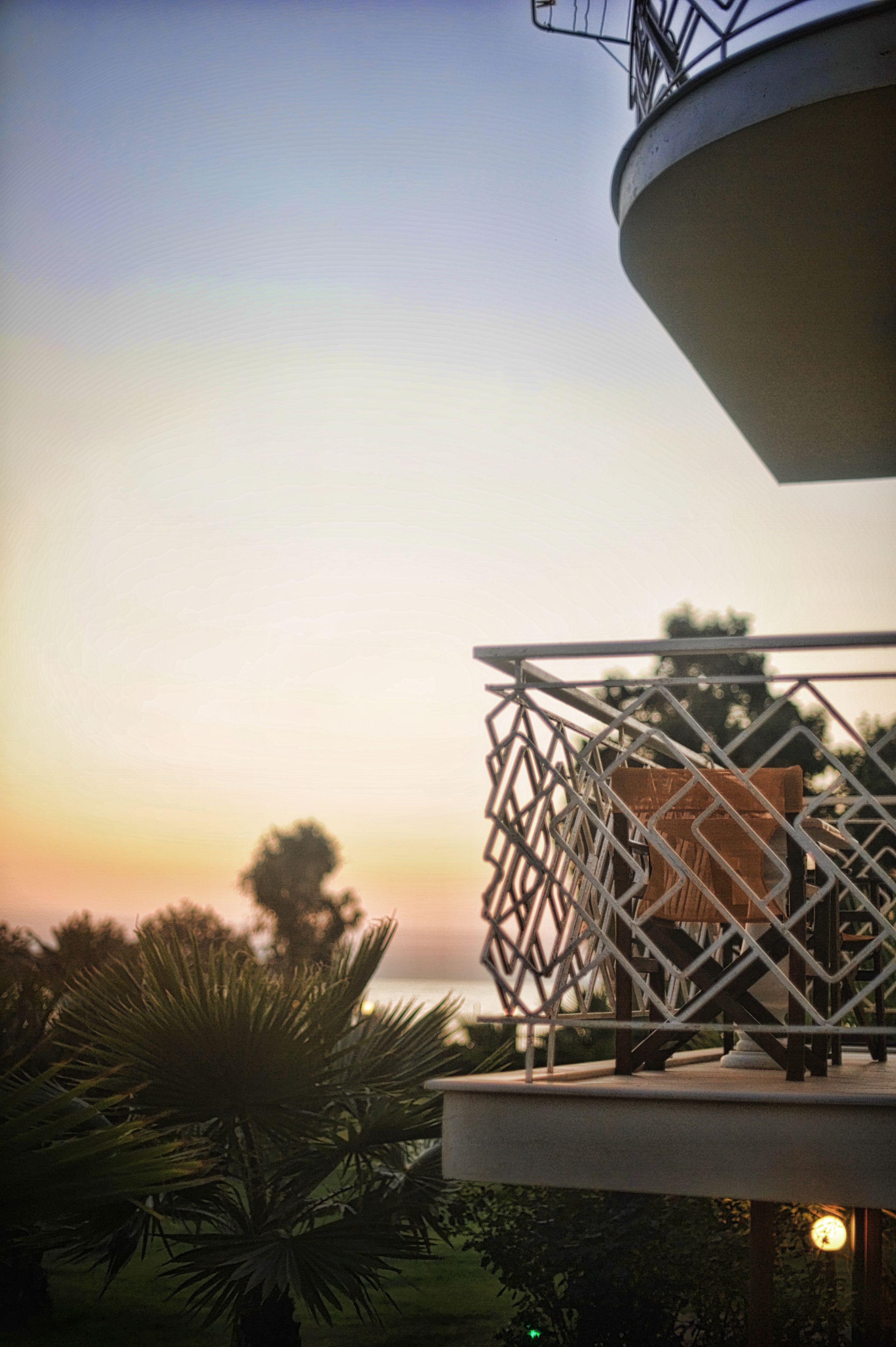 A balcony with a metal railing overlooking a sunset.