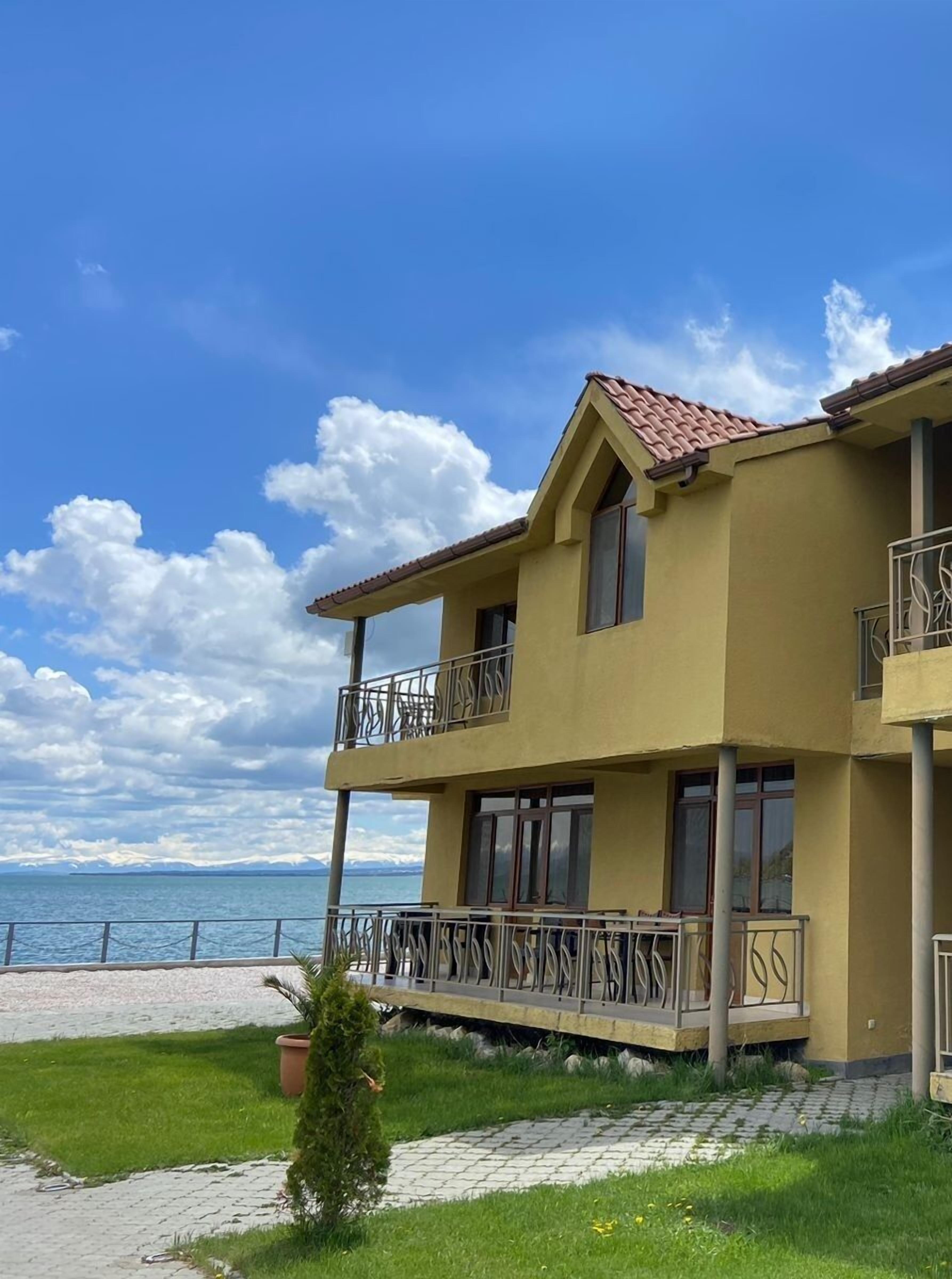Un edificio de dos pisos con balcones, techo de tejas y vista al mar.