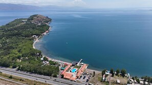 Vista aérea de una zona costera con playa, piscina y carretera.