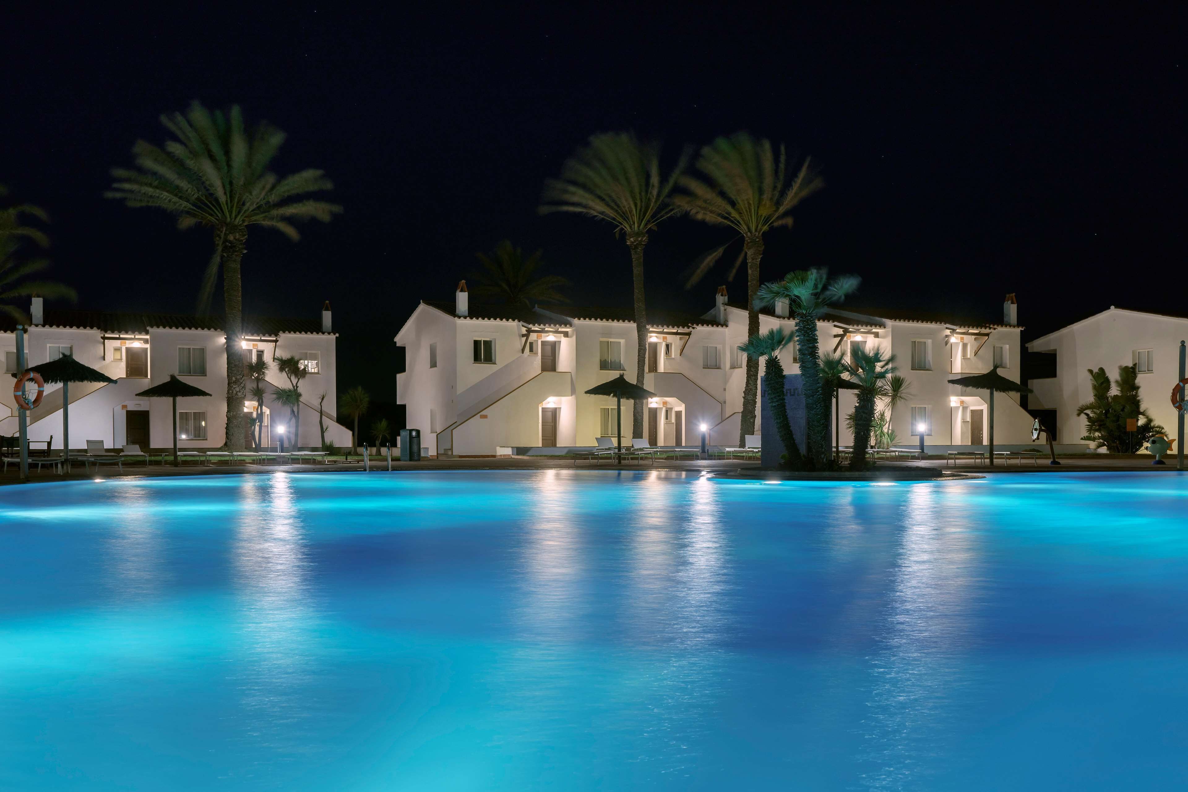 Una piscina al aire libre, sombrillas, sillones reclinables de piscina