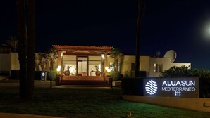 Entrada d'un hotel amb un rètol que diu "ALUASUN MEDITERRÁNEO" i una antena parabòlica.