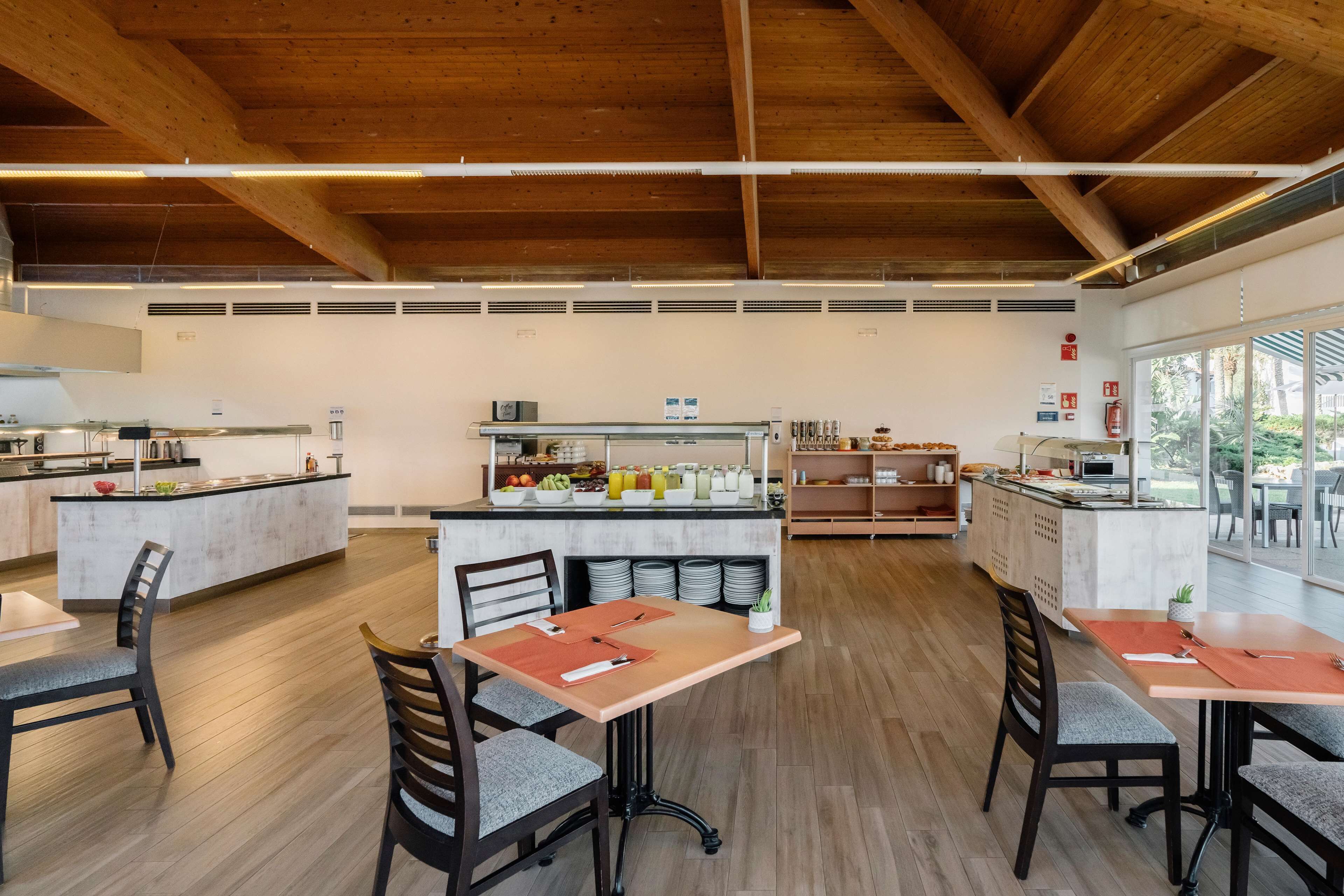 Un vaste espace de salle à manger intérieur doté d’un plancher en bois, d’un îlot central avec un comptoir de cuisine et de différents espaces pour s’asseoir.