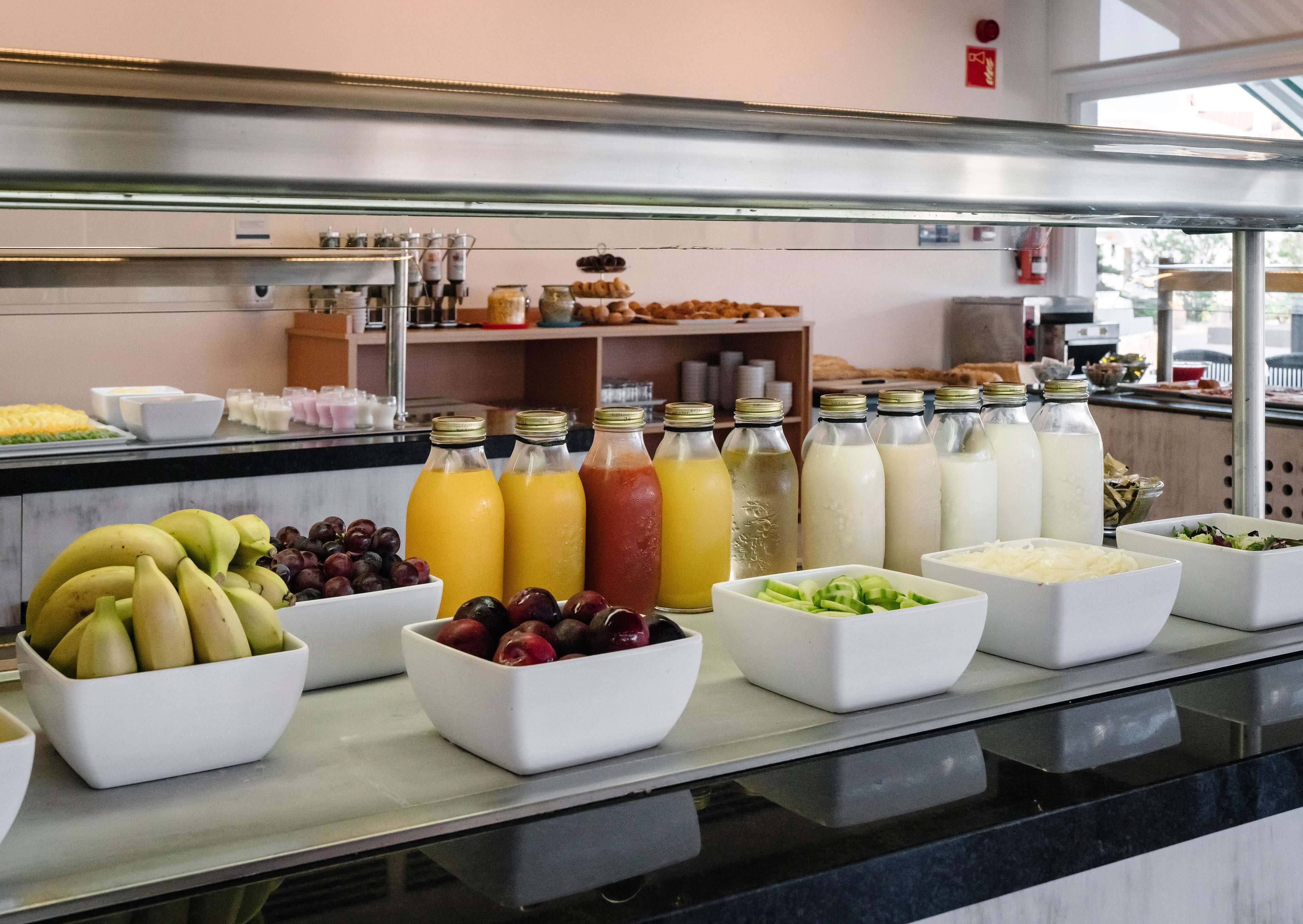 A breakfast buffet with various fruits, juices, and dairy products.