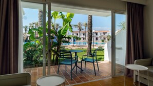 Una habitació amb una porta corredissa de vidre que dona a una zona de piscina, una taula petita i un sofà.