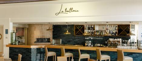 A restaurant with wooden beams, wicker chairs, and a bar area with a stone countertop.