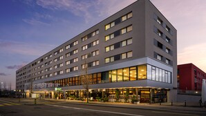 A modern hotel with a two-story structure, large windows, and a ground-level restaurant. - Holiday Inn Zurich - Messe by IHG (Zürich)