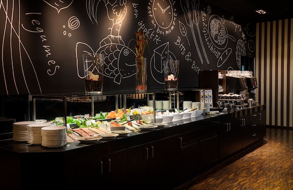 A buffet area with various food items and a chalkboard wall with food-related drawings.