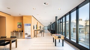 A corridor with a foosball table, a reception desk, and a poster titled "Energy Corner". - Holiday Inn Zurich - Messe by IHG (Zürich)