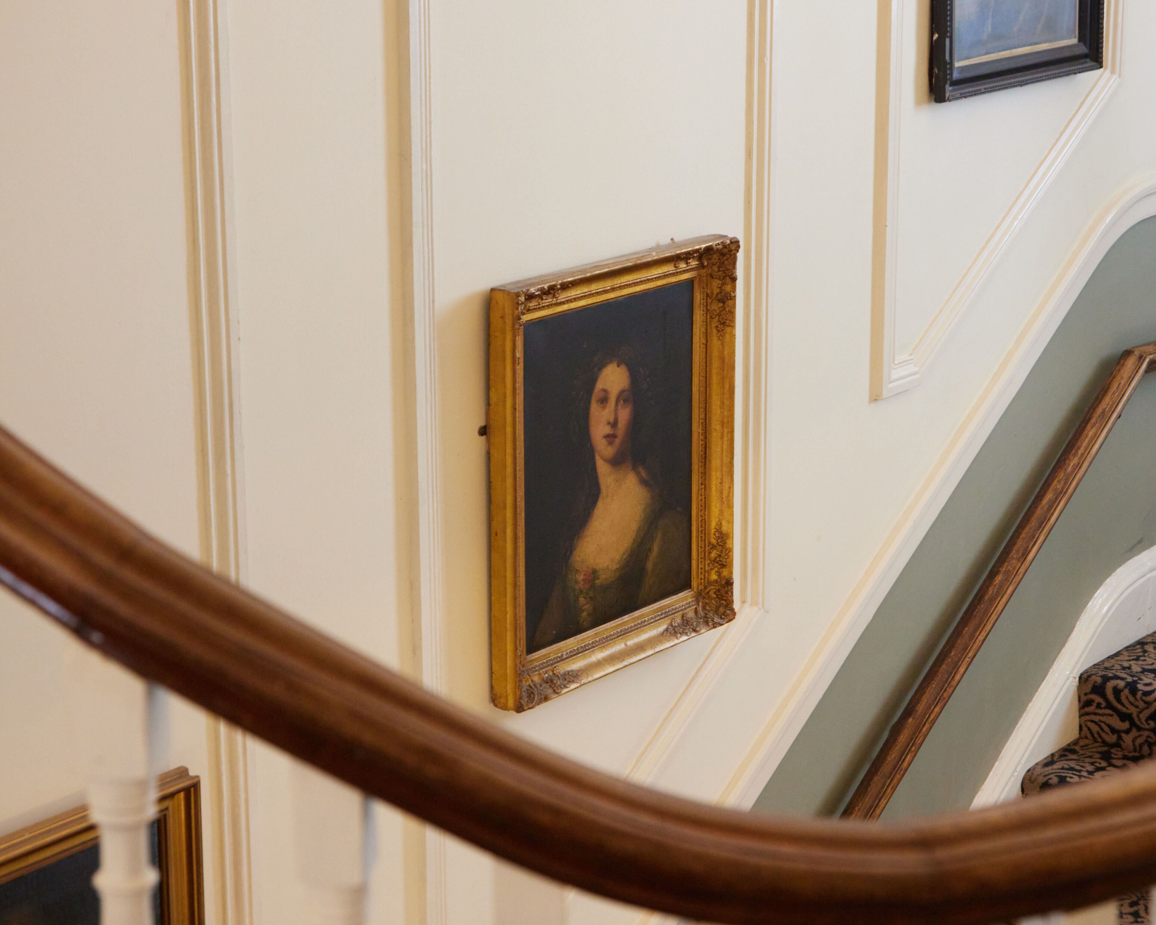 A staircase with a wooden handrail and a framed portrait on the wall.