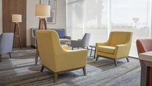 A hotel lobby with a large window, a sofa, two armchairs, and a floor lamp. - Holiday Inn Express Guadalajara Iteso by IHG (Tlaquepaque)