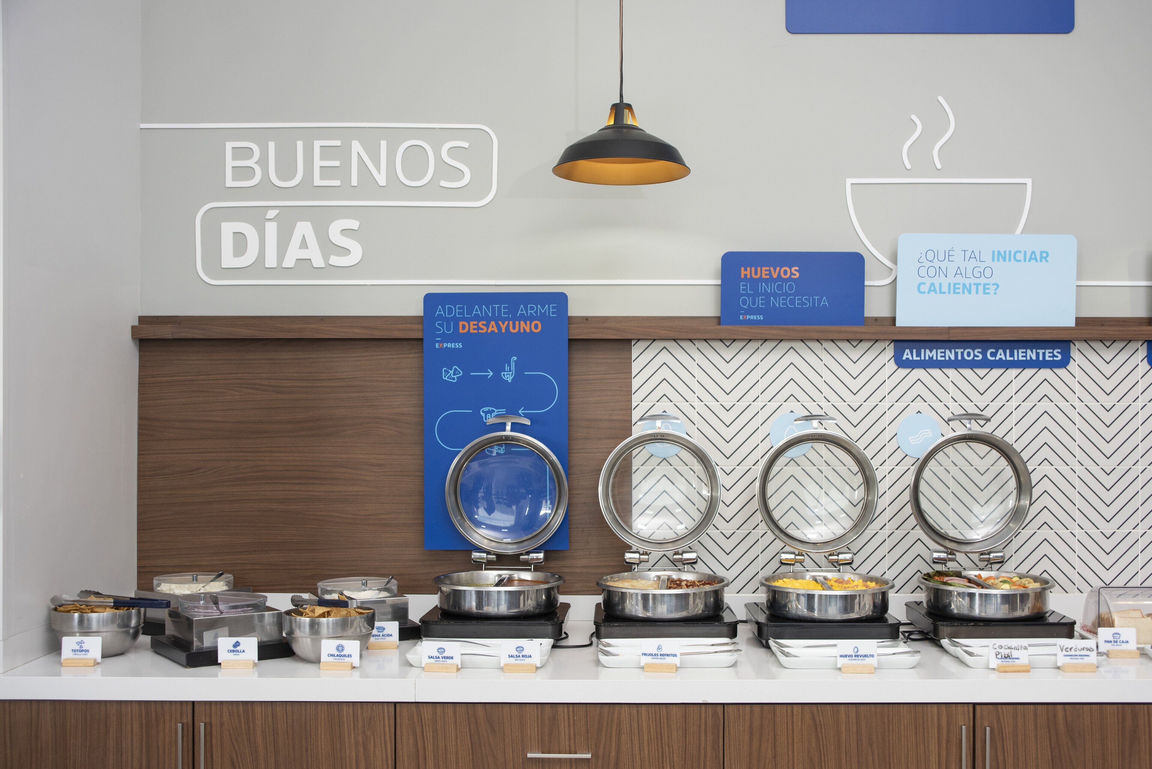 A breakfast buffet setup with labeled food stations and a welcoming sign.