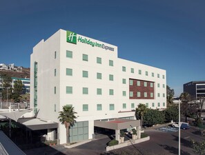 Un bâtiment de la chaîne Holiday Inn Express, doté d’un design moderne, avec un toit plat et un grand espace d’entrée agrémenté d’une allée couverte.