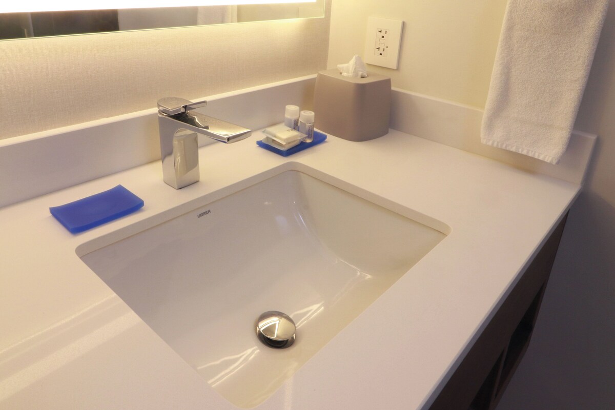 A modern bathroom with a white sink, a mirror, and a towel rack.