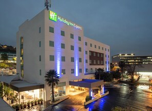 A Holiday Inn Express hotel with a modern facade, multiple windows, and a well-lit entrance area. - Holiday Inn Express Guadalajara Iteso by IHG (Tlaquepaque)