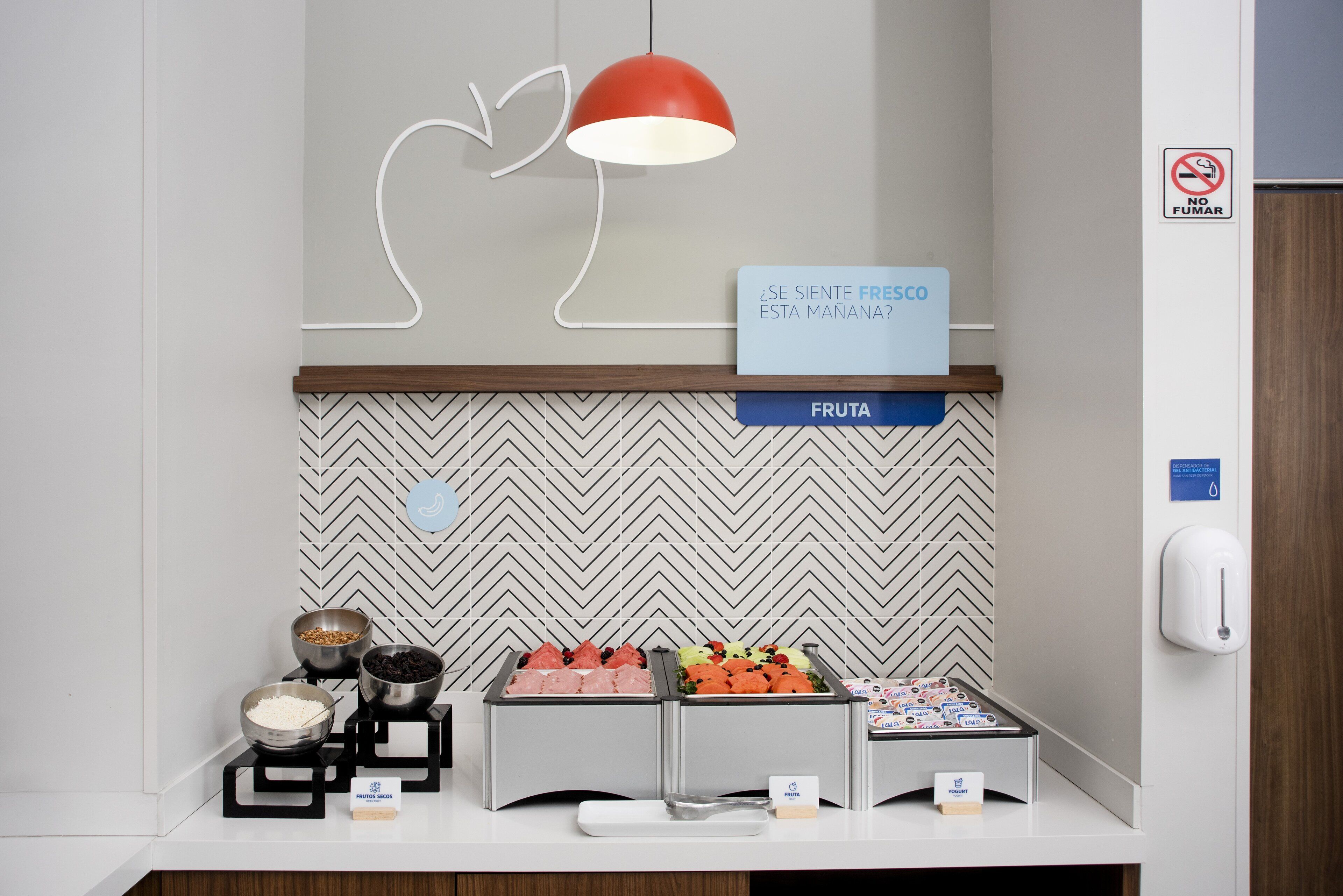 A breakfast buffet area with various food items and a sign in Spanish.
