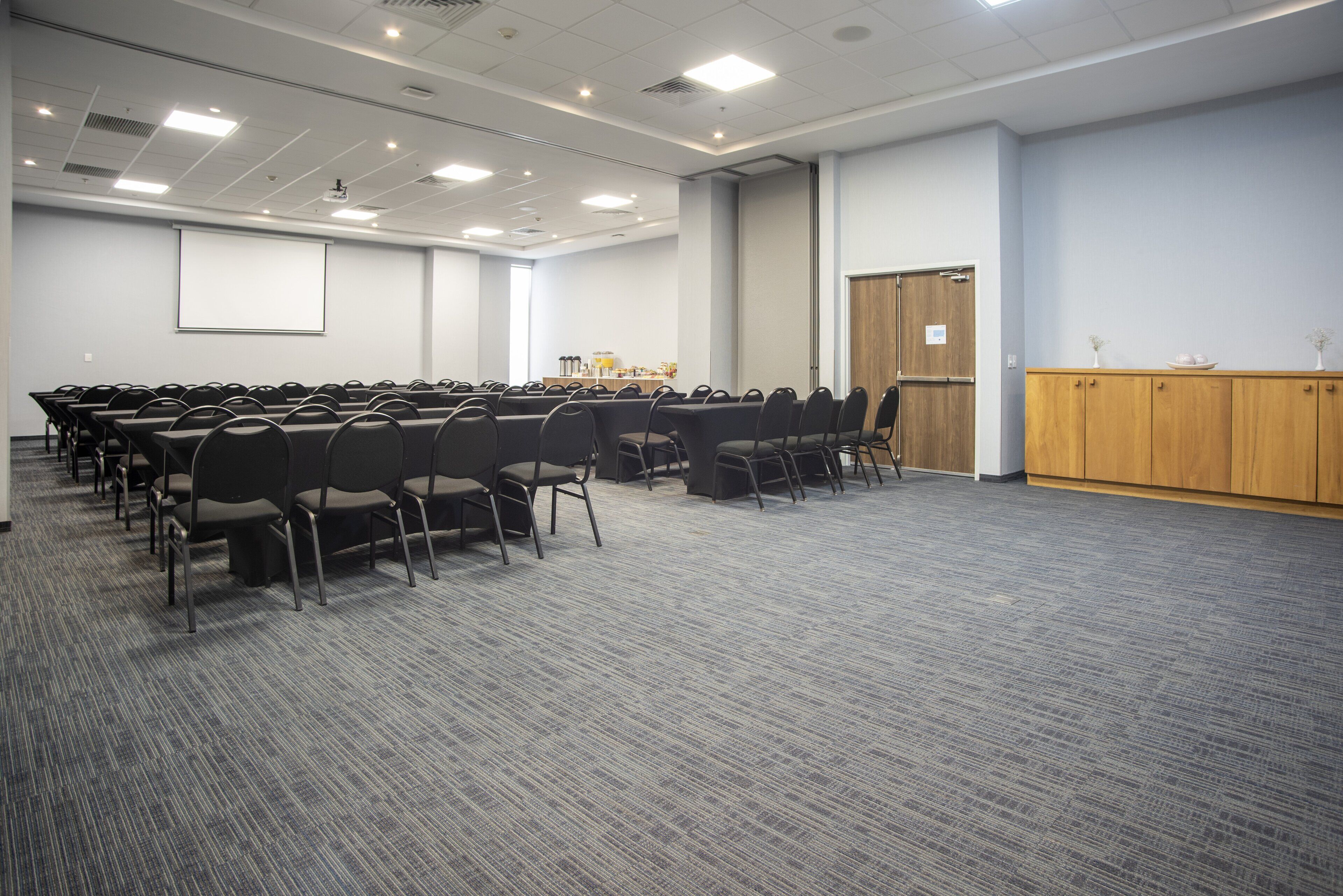 A conference room with rows of chairs, a projector screen, and a podium.