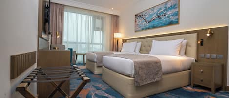 A hotel room with a bed, a desk, a chair, a TV, and a painting on the wall.