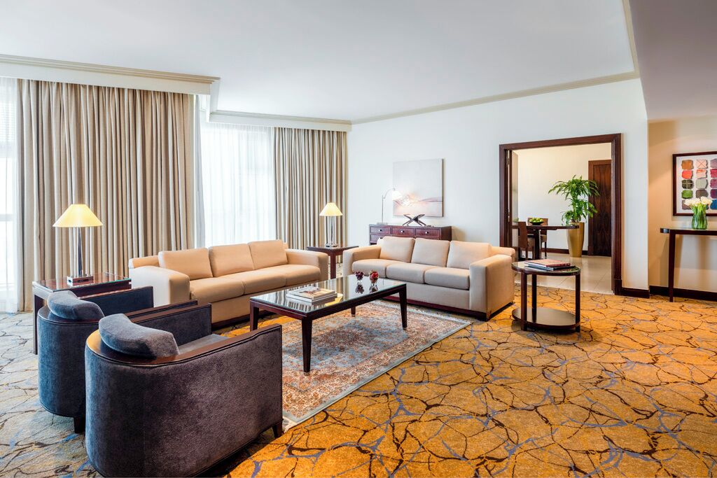 A hotel lobby with two sofas, a coffee table, a rug, and a small side table with a lamp.