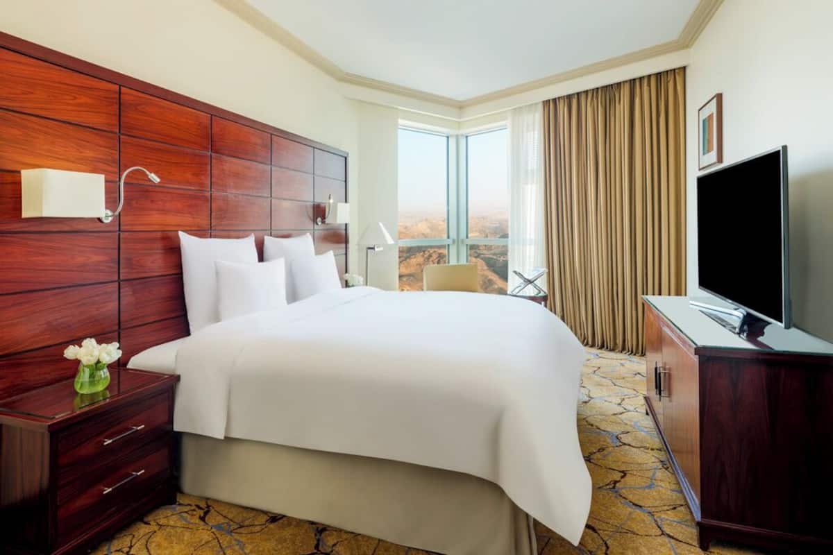 Une chambre d’hôtel avec un grand lit, une télévision, un bureau et une vue sur l’extérieur.