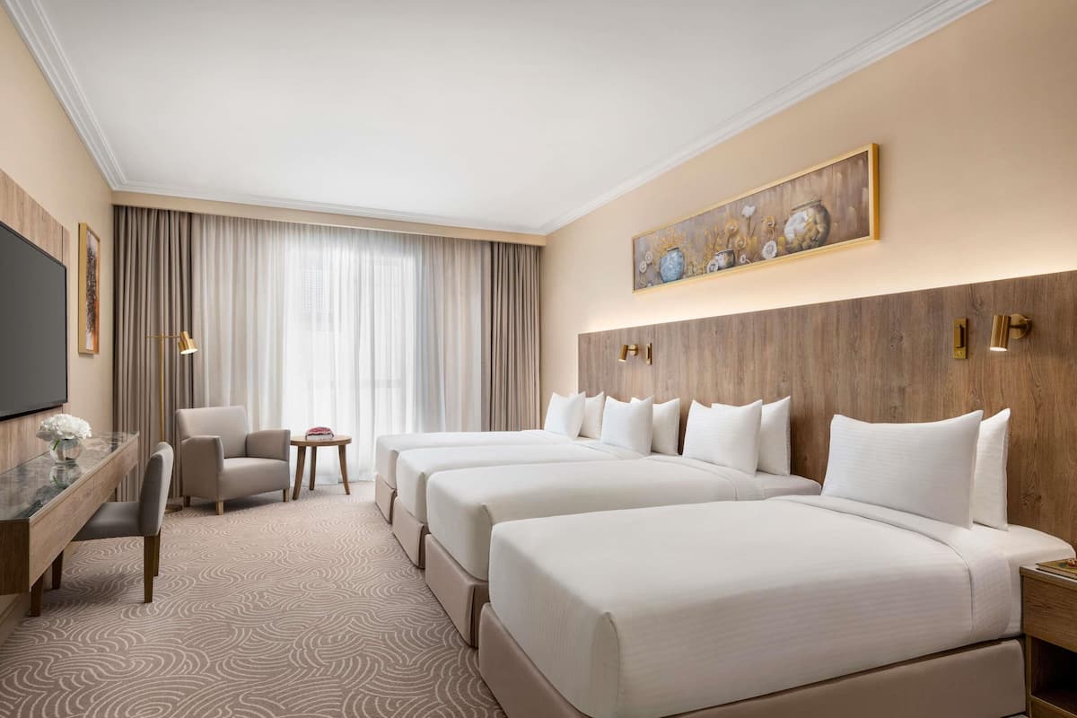 Une chambre d’hôtel avec un grand lit, un bureau, une chaise, une télévision et un tableau au mur.
