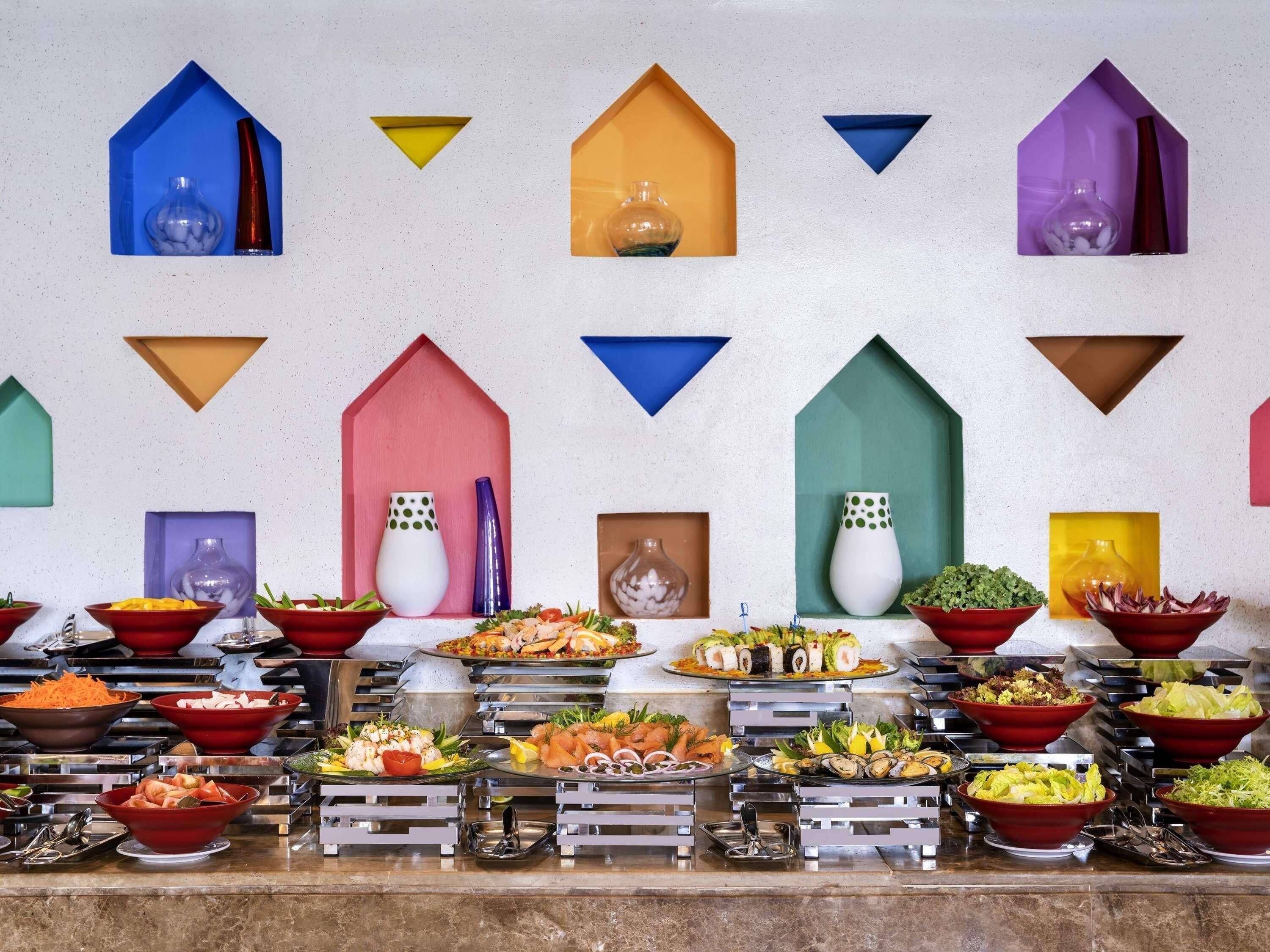 A buffet with various dishes and colorful geometric wall decorations.