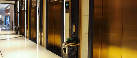 Un moderno vestíbulo de hotel con un mostrador de recepción de mármol, ascensores y un suelo limpio y pulido.