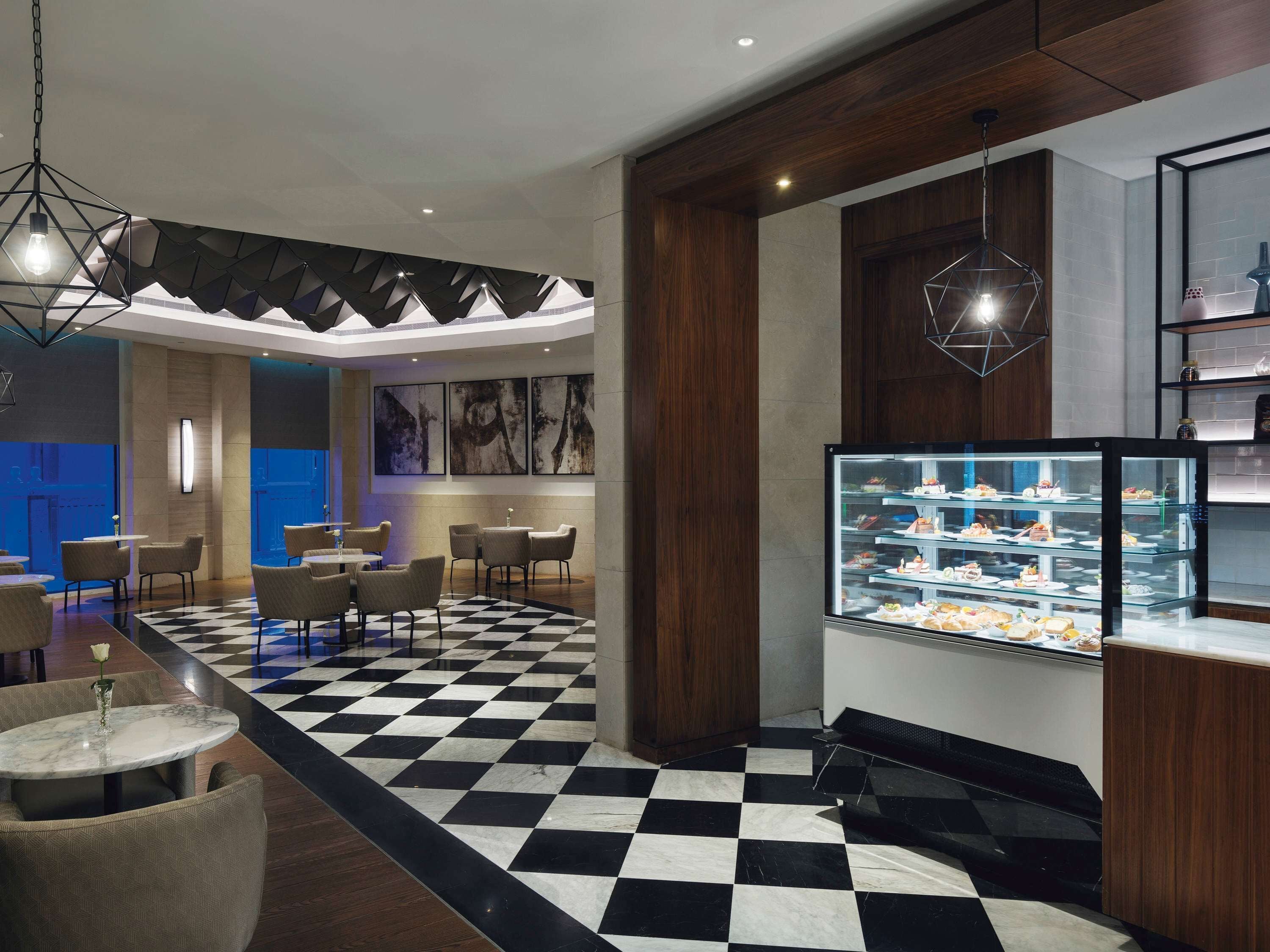 Un hall d’hôtel moderne avec un sol à carreaux, un espace salon et un présentoir de desserts.